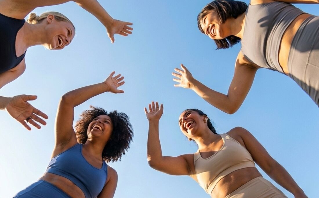 Grupo de amigas rindo de braços erguidos depois do treino